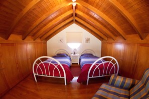 A room with two beds, wooden ceiling beams, a nightstand, and a chair. - Bungalow with heated saltwater pool (Calheta)