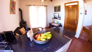 Une cuisine avec un plafond en bois, un plan de travail en pierre, un panier de fruits et une cheminée.