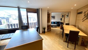 Een moderne woonkamer met een eethoek, grote ramen en uitzicht op de stad.