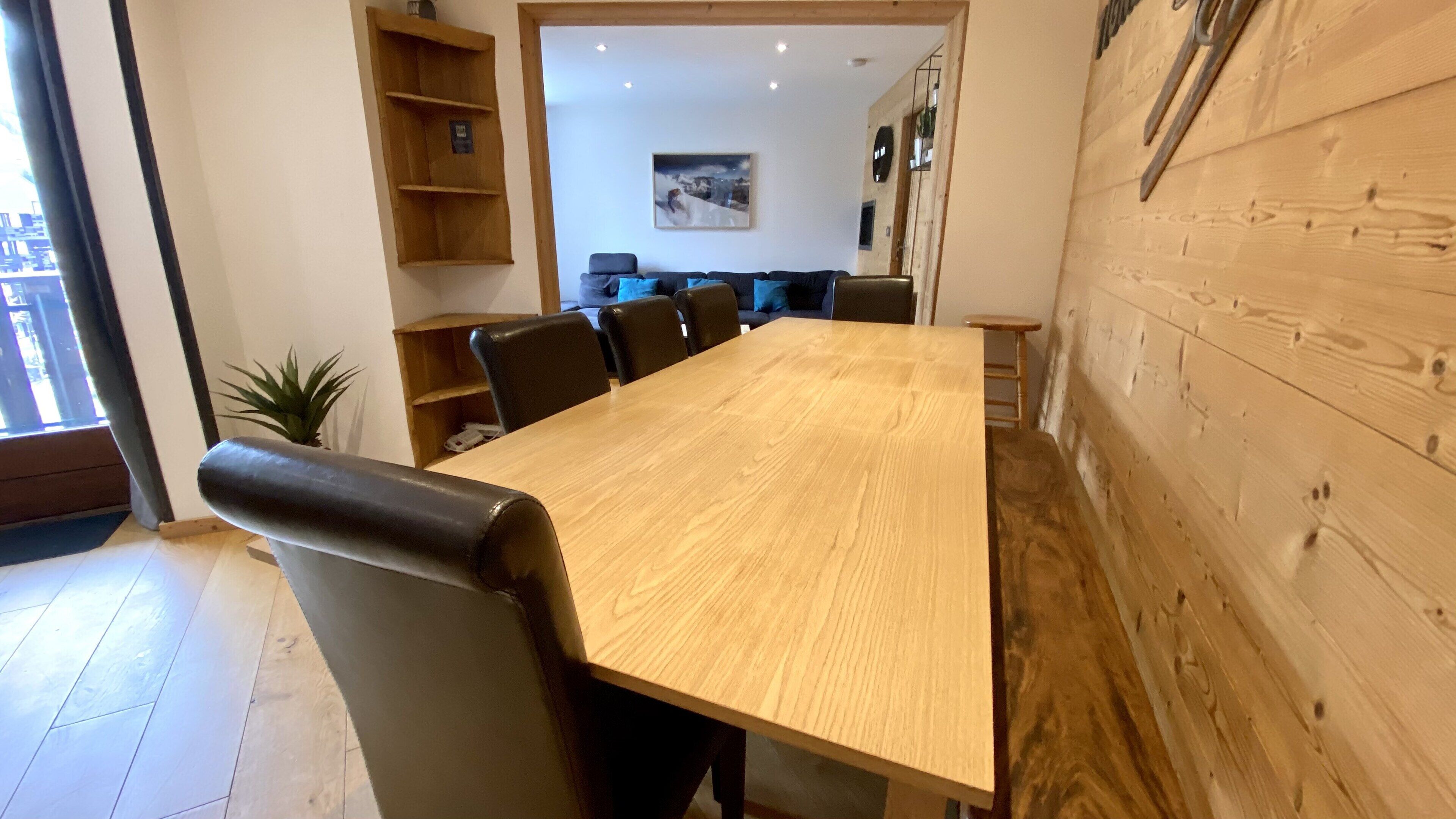 A conference room with a wooden table, black leather chairs, a bookshelf, and a painting on the wall.