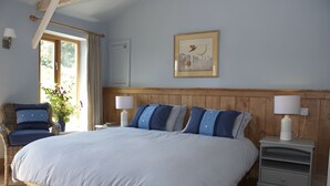 Una camera da letto con un letto grande, due comodini, una sedia e una finestra con tende.