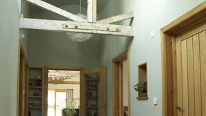 Un corridoio in legno con una ventola a soffitto, una porta con uno specchio e una piccola mensola con una pianta.