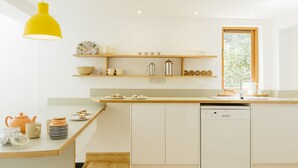 A modern kitchen with white cabinetry, a wooden countertop, and a yellow pendant light. - Contemporary cottage retreat in secluded valley near sea. Sleeps 8 (Bude)