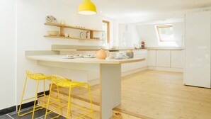 A modern kitchen with a central island, yellow bar stools, and a bright yellow pendant light. - Contemporary cottage retreat in secluded valley near sea. Sleeps 8 (Bude)