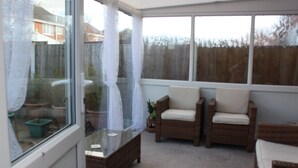 A sunroom with wicker furniture, a glass coffee table, and potted plants. - Mayfield  stay 4 to 30     days maybe  longer .car parking for 2 cars  on  drive (Thornton Cleveleys)