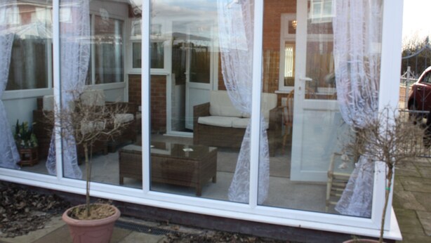 A conservatory with a glass door, potted plants, and a seating area with a sofa and coffee table. - Mayfield  stay 4 to 30     days maybe  longer .car parking for 2 cars  on  drive (Thornton Cleveleys)