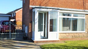 A residential building with a brick facade, a white-framed window, and a metal gate. - Mayfield  stay 4 to 30     days maybe  longer .car parking for 2 cars  on  drive (Thornton Cleveleys)