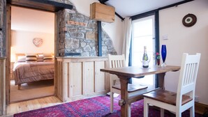 A cozy room with a stone wall, wooden furniture, a bed, and a dining area. - Bay Cottage, a section of Ebbingford Manor, 850 yr old manor house by beach&town (Bude)