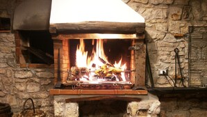 Una chimenea de piedra con estufa de leña, una cesta tejida y un sillón de madera.
