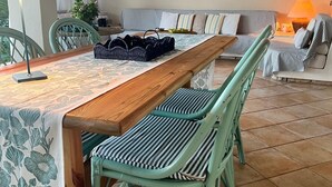 A dining area with a wooden table and chairs, a striped sofa, and a lamp. - Villa with garden just 200 meters from the beautiful beach of Costa Rei (Costa Rei)