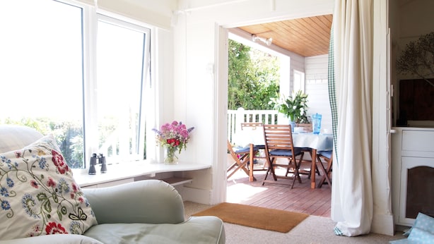 A cozy living room with a sofa, a dining area with a table and chairs, and a view of the outdoors. - Beach front location, Pet friendly, Full of charachter, Private garden, Sea view (Selsey)