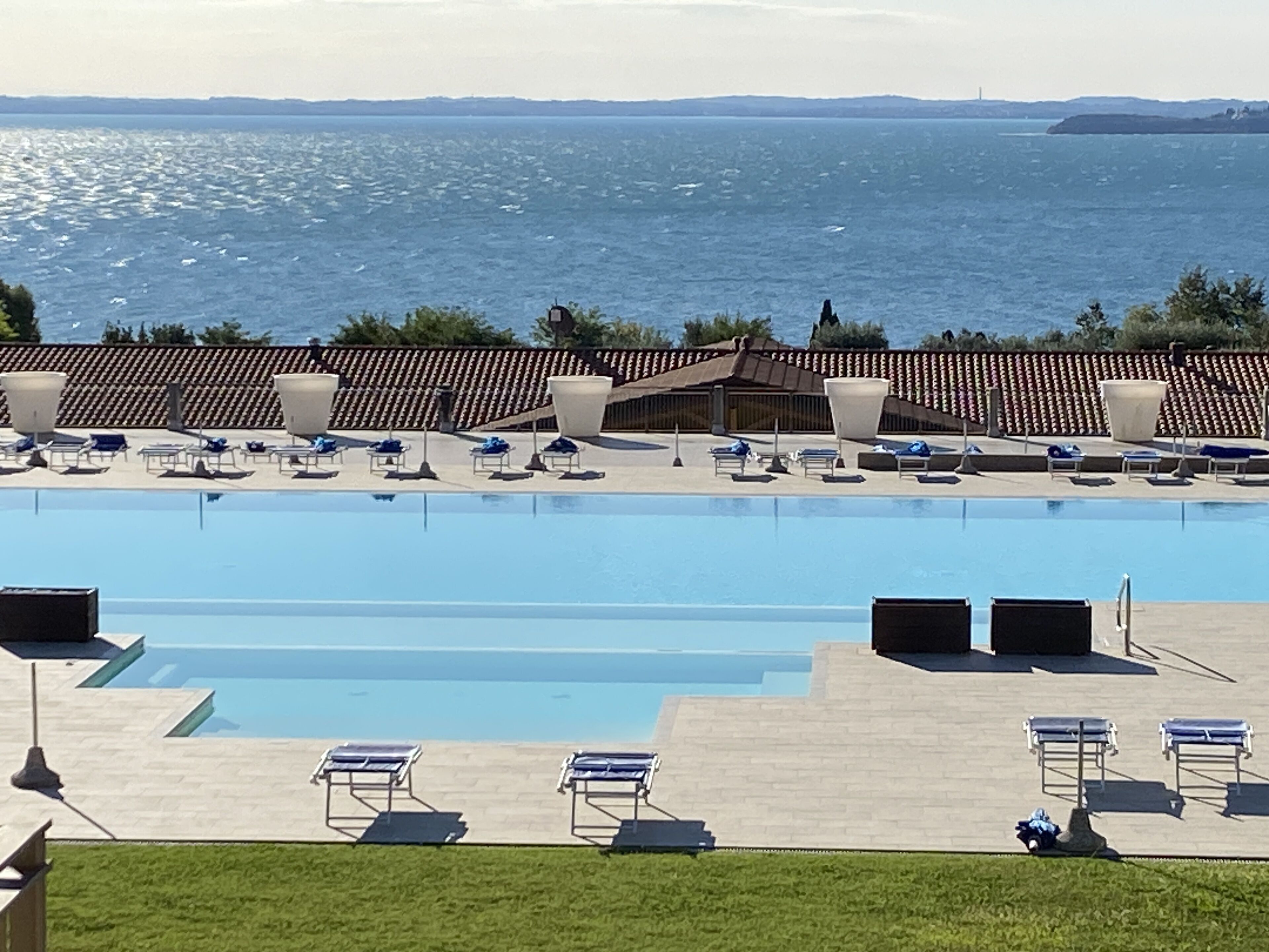 A large swimming pool with sun loungers and a view of the sea.