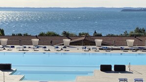 Une grande piscine avec des chaises longues et vue sur la mer.