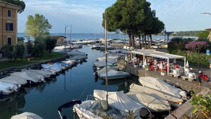 Un port de plaisance avec des bateaux amarrés, un café doté d’une terrasse, et un bâtiment surmonté d’un toit en tuiles.