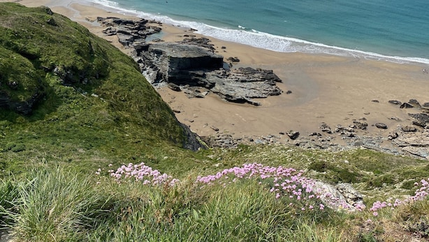 Eine Küstenlandschaft mit einem felsigen Strand, einer Klippe und einer entfernten Insel.