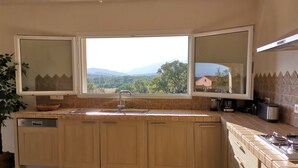 A kitchen with a large window, wooden cabinets, a sink, and a stove. - VERY QUIET SPACIOUS VILLA, SEA AND MOUNTAIN VIEWS, 500M FROM THE BEACH (Zonza)