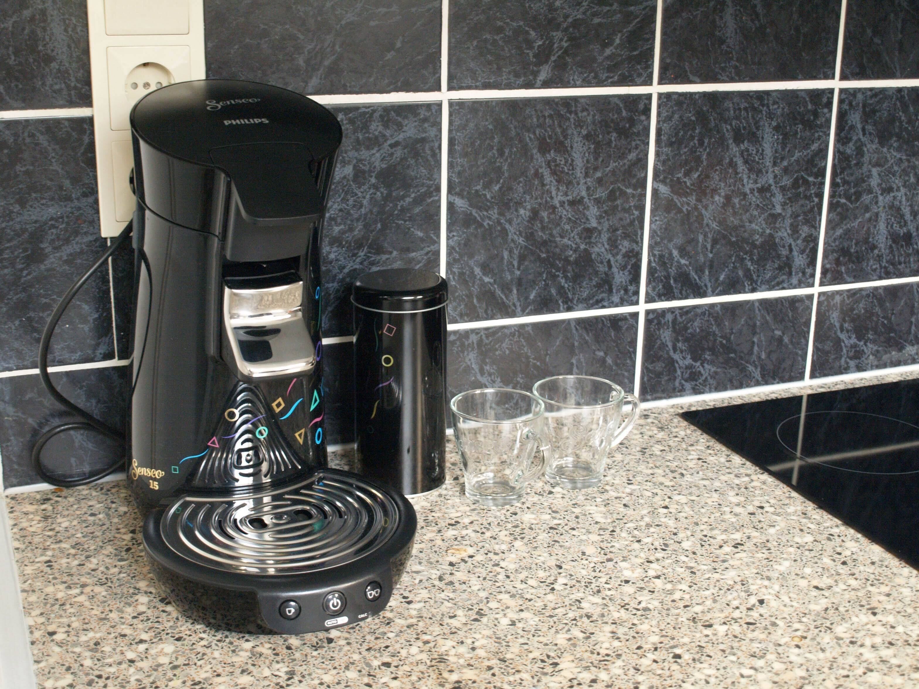 Máquina de café sobre uma bancada de cozinha com painel de azulejos.