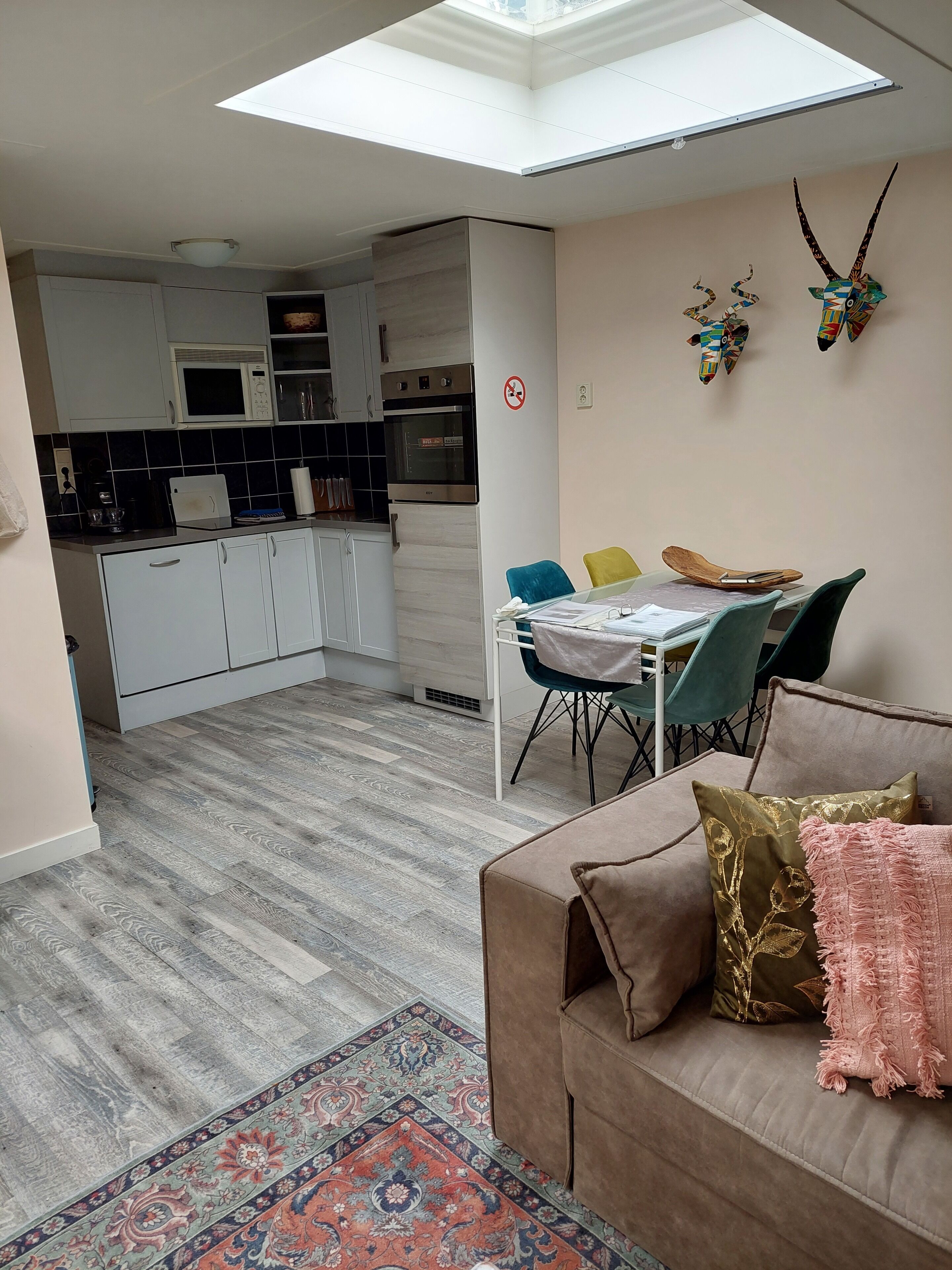 Eine moderne Wohnung mit Küche, Essbereich und Wohnzimmer, ausgestattet mit einer Couch und einem gemusterten Teppich.