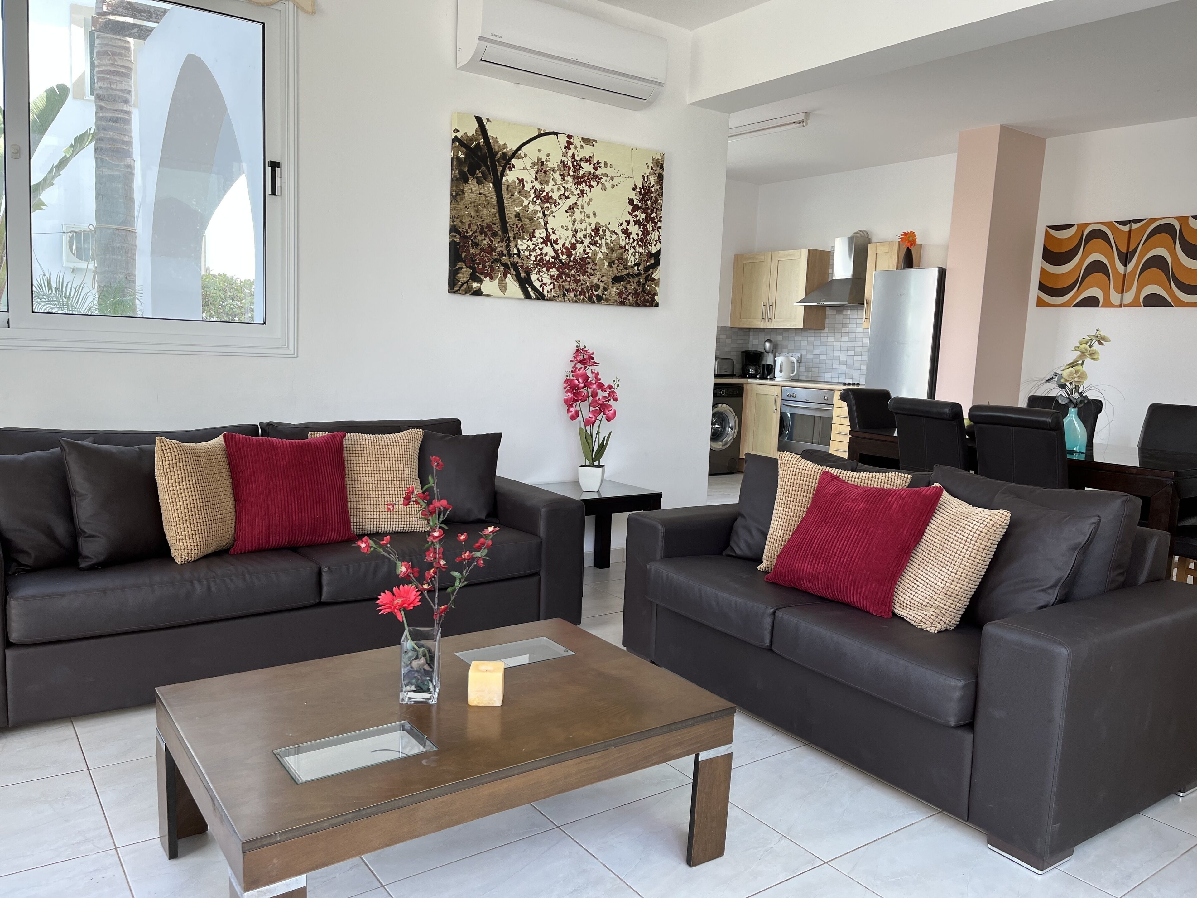 Ein modernes Wohnzimmer mit zwei dunklen Sofas, einem Couchtisch und einer Küche im Hintergrund.