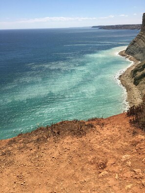 Paisatge costaner amb un penya-segada rocosa i una vista clara de l'oceà.