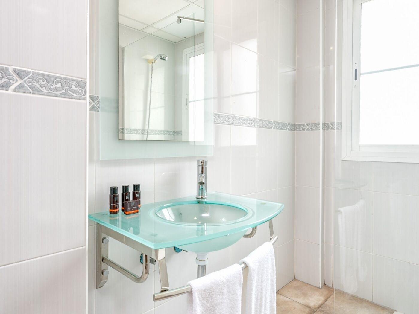 A bathroom with a glass sink, a mirror, and a shower.