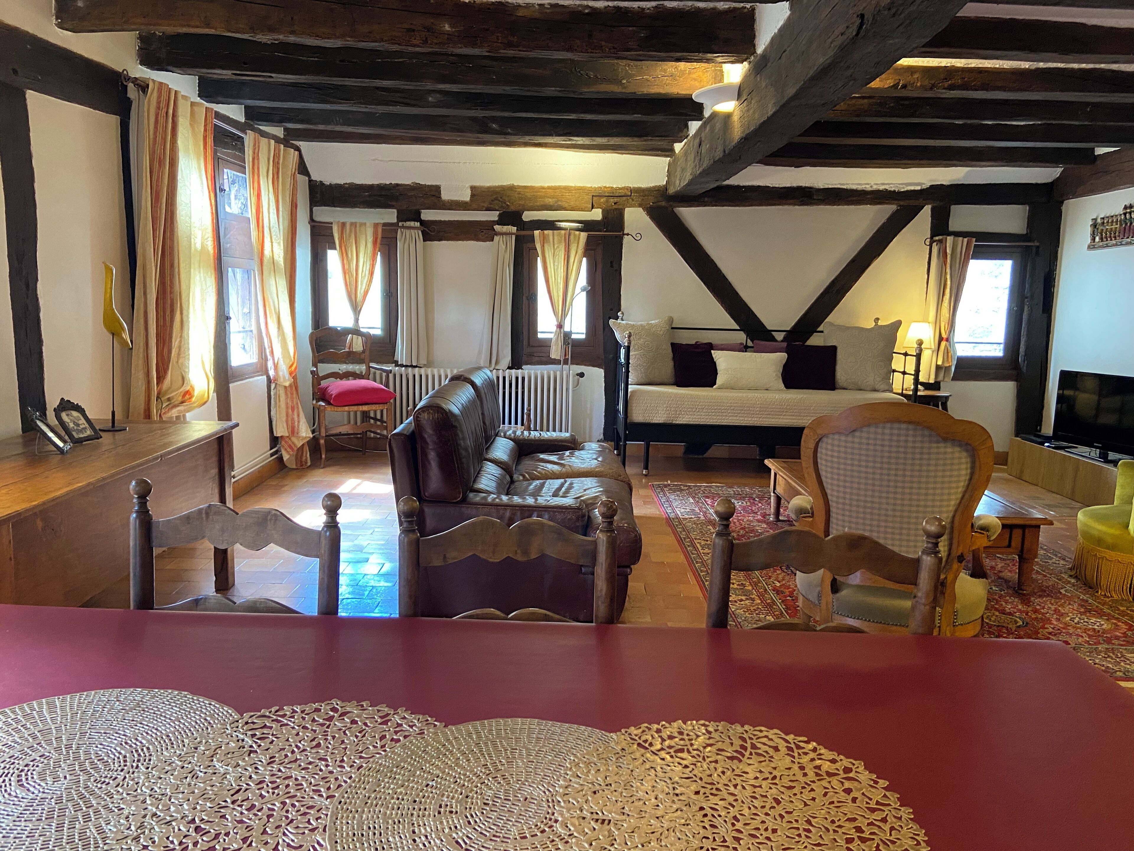 Een gezellige kamer met houten plafond, een bank, een bed en een televisie.
