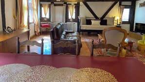 A cozy room with a wooden ceiling, a sofa, a bed, and a television.