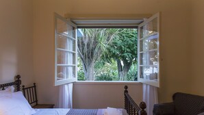 Quarto com cama, cadeira e janela com persiana aberta.