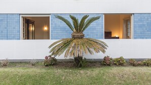 Um edifício com fachada em azulejos azuis, uma palmeira ao centro e uma placa sobre a entrada.