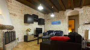 Uma sala de estar aconchegante com paredes de pedra, lareira, sofá e televisão.