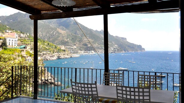 A terrace with a table and chairs overlooking a coastal town and the sea. - Amalfi Coast - Il Monaco, Three Bedrooms villa with equipped platform on the sea (Ravello)
