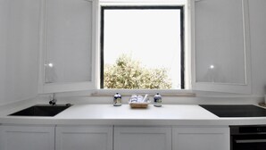 A kitchen with a window, white cabinets, a black sink, and two decorative jars on the counter. - Amalfi Coast - Il Monaco, Three Bedrooms villa with equipped platform on the sea (Ravello)