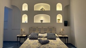 A bedroom with a patterned bedspread, two bedside tables with lamps, a headboard, and a series of illuminated niches on the wall. - Amalfi Coast - Il Monaco, Three Bedrooms villa with equipped platform on the sea (Ravello)