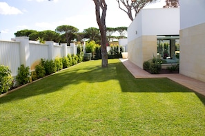 A well-maintained lawn, a white fence, and a building with a glass entrance.