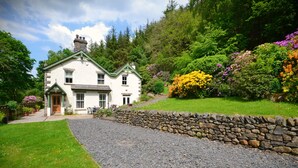 A white house with a stone wall and a gravel path leading to the entrance. - Spacious, detached & private Lakeland hideaway near Cark / Cartmel (Cumbria)