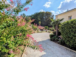 A garden with a gravel path leading to a building with a red roof.