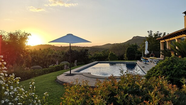 A swimming pool with a surrounding garden and a view of hills during sunset. - Country villa with pool, private garden and barbecue near the beach OFFER June (Manacor)