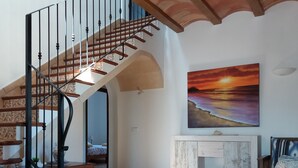 A spacious living area with a wooden staircase, a painting of a sunset, and a tiled floor. - Country villa with pool, private garden and barbecue near the beach OFFER June (Manacor)