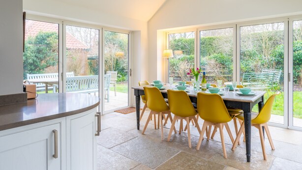 Una cucina moderna con zona pranzo, ampie finestre e vista sul giardino.