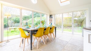 Una cucina luminosa con ampie finestre, un tavolo da pranzo con sedie gialle e vista sul giardino.