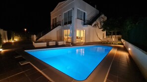 Une maison moderne dotée d’une piscine, d’un balcon et d’un intérieur bien éclairé.