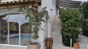 Un espace aménagé au bord de la piscine, avec une grande fenêtre, une plante en pot et un escalier en pierre.