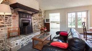 Una sala de estar acogedora con chimenea de piedra, un sofá de cuero y una mesa de centro de vidrio.
