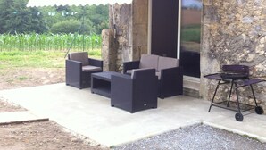 An outdoor patio with wicker furniture, a barbecue grill, and a stone wall. - renting a beautiful villa in the moors (Lahosse)
