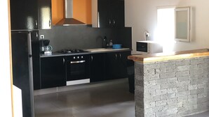 A kitchen with black cabinets, a gas stove, a microwave, and a sink. - renting a beautiful villa in the moors (Lahosse)