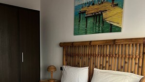 A bed with a wooden headboard, a painting of a pier, and a wardrobe. - Apt71 Porto Antigo 2 Two Bed Penthouse with Shared Pool and Panaromic Sea Views. (Santa Maria)