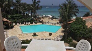 A poolside view with a clear view of the ocean, lounge chairs, and palm trees. - Apt71 Porto Antigo 2 Two Bed Penthouse with Shared Pool and Panaromic Sea Views. (Santa Maria)
