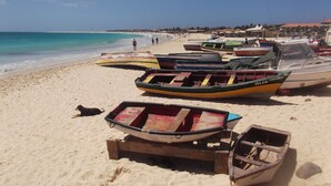 A beach with several boats parked on the sand, a dog lying nearby, and a clear blue sky. - Apt71 Porto Antigo 2 Two Bed Penthouse with Shared Pool and Panaromic Sea Views. (Santa Maria)