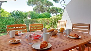 A wooden table with breakfast items including croissants, a plate of fruit, and a bowl of nuts. - Freshly renovated with AirCo, ground floor apt with terrace, garden and pool (Vilamoura)