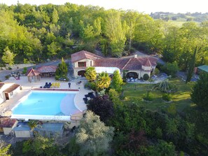 A large house with a swimming pool, outdoor seating, and a garden.